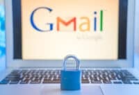 Blue closed metal lock on laptop touchpad with Gmail logo on the laptot screen in the background. Gmail security issues concept.